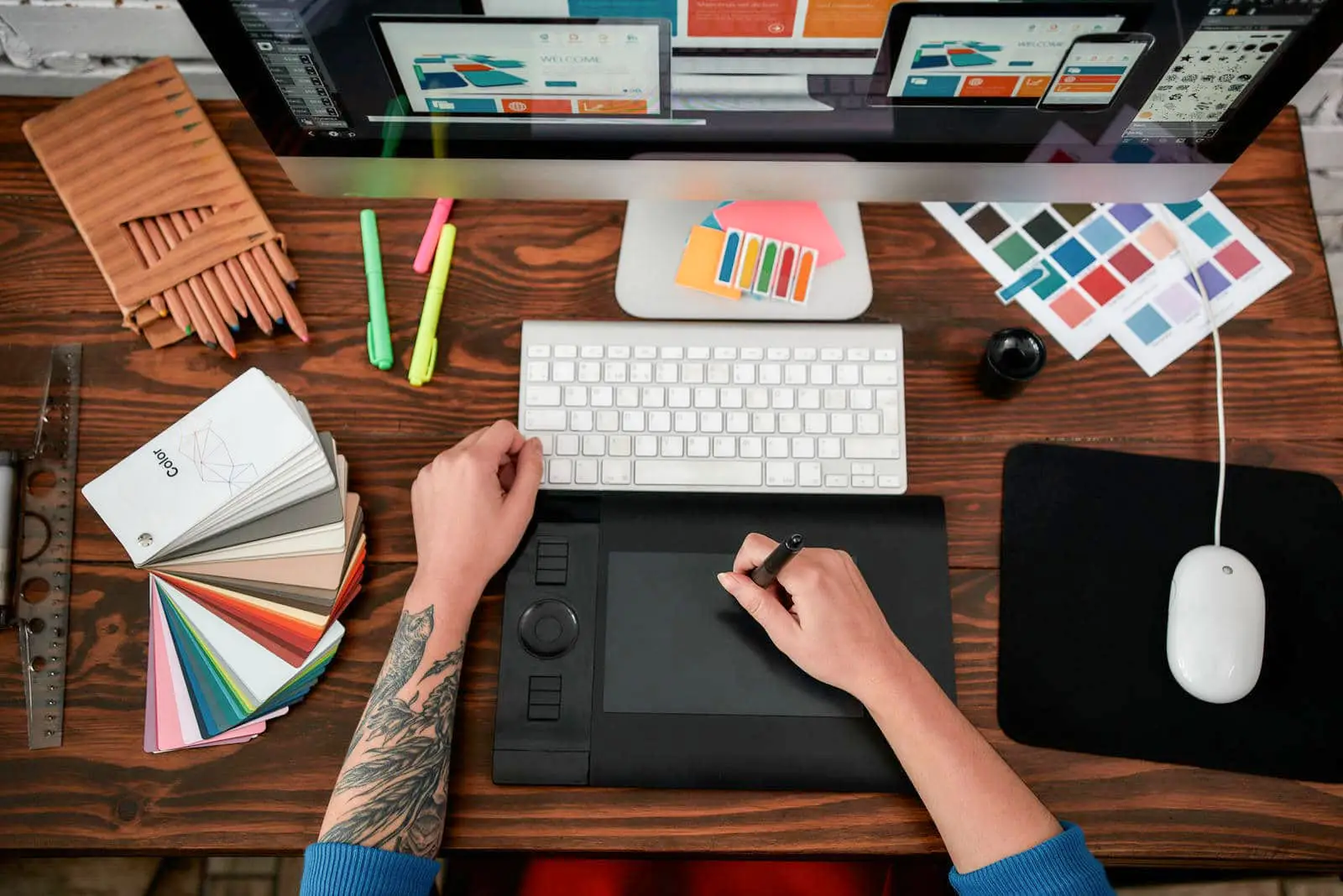 Top view of a designer's desk with color swatches, a drawing tablet, and a computer, showcasing the detailed approach of web designers near me to website design