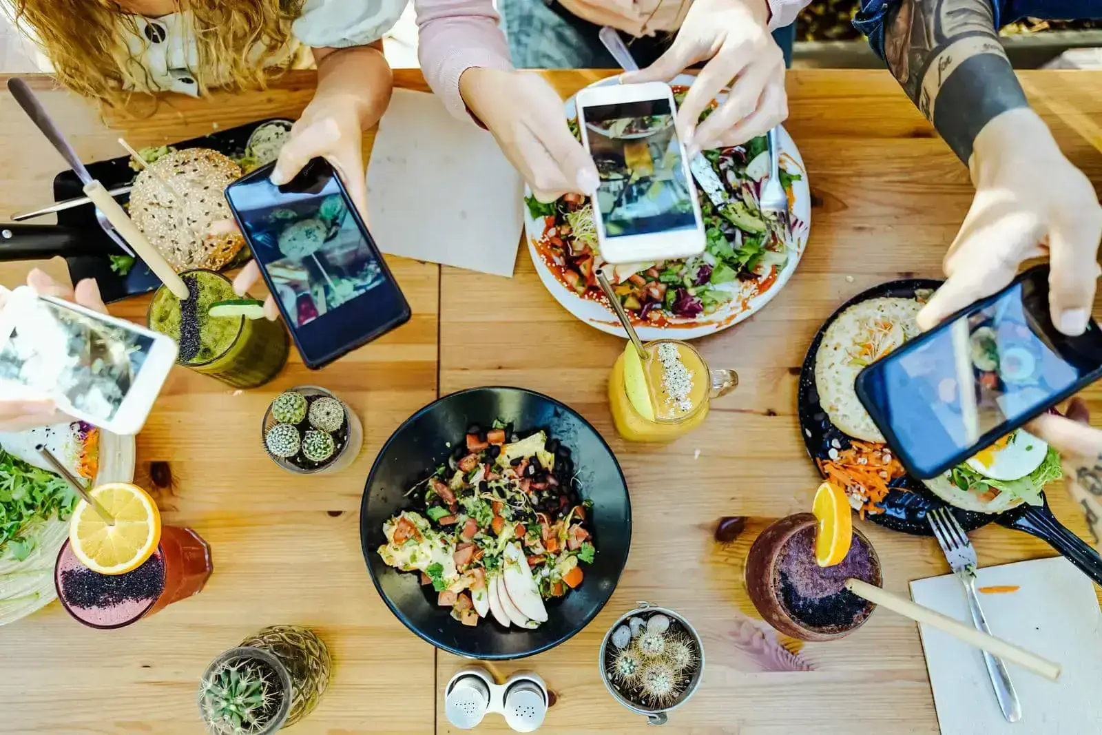 Multiple people taking photos of their food at a restaurant, showcasing effective social marketing strategies.