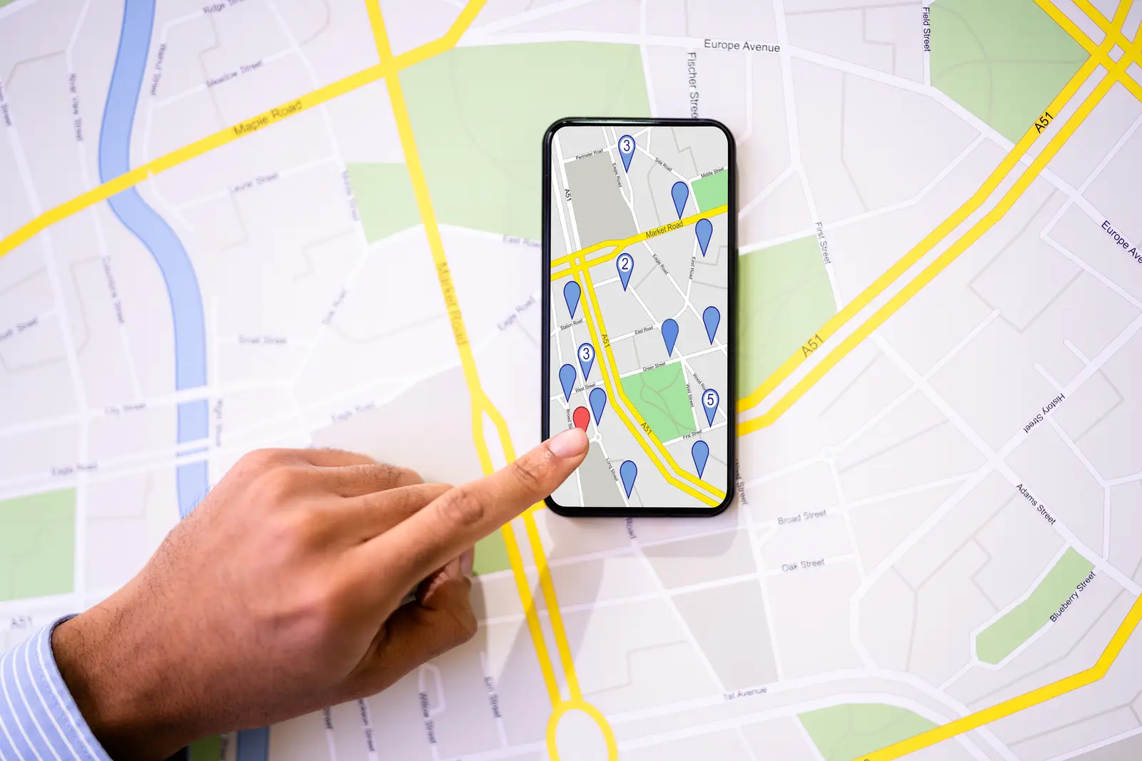 A hand pointing to a location on a map displayed on a smartphone screen, representing a website design agency near me.