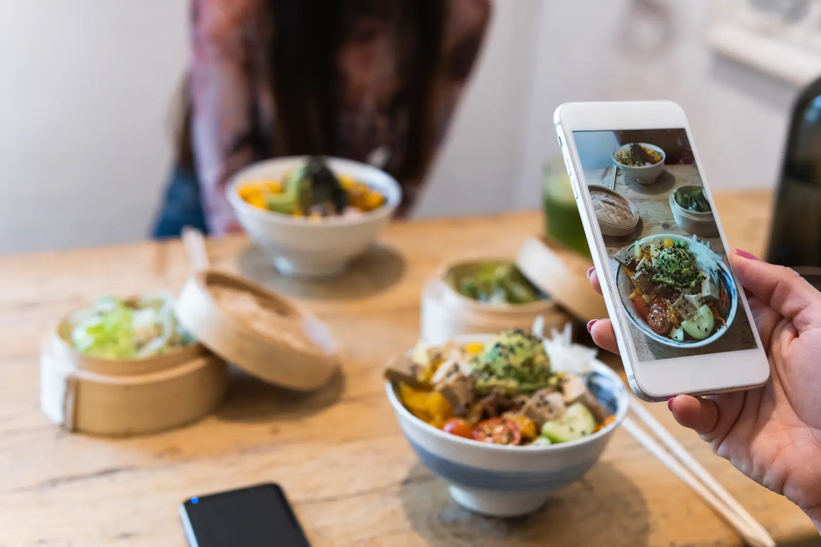 Person taking a photo of a dish in a restaurant, highlighting SEO strategies for small businesses.