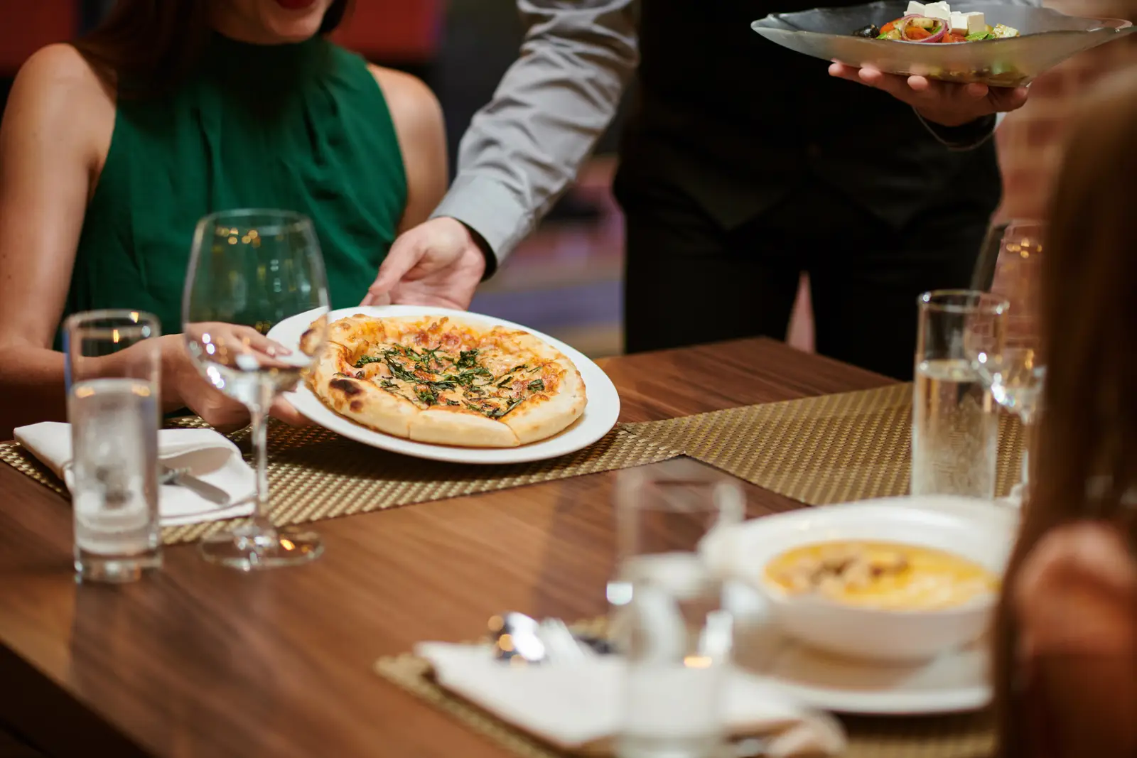 Waiter serving pizza at a restaurant, showcasing SEO strategies for small businesses.