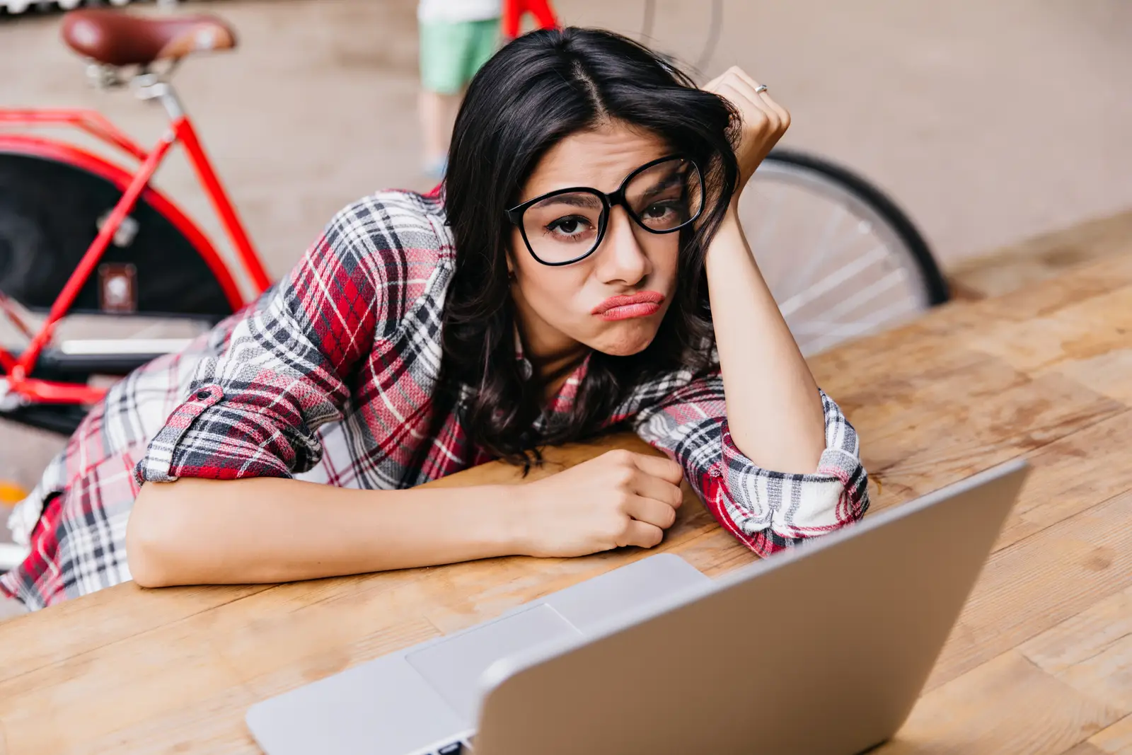 Woman feeling frustrated while working on a laptop, depicting challenges in SEO for small business owners.