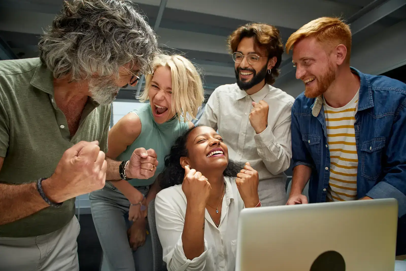 Team of diverse colleagues celebrating around a laptop, exemplifying the best website design companies for small business.